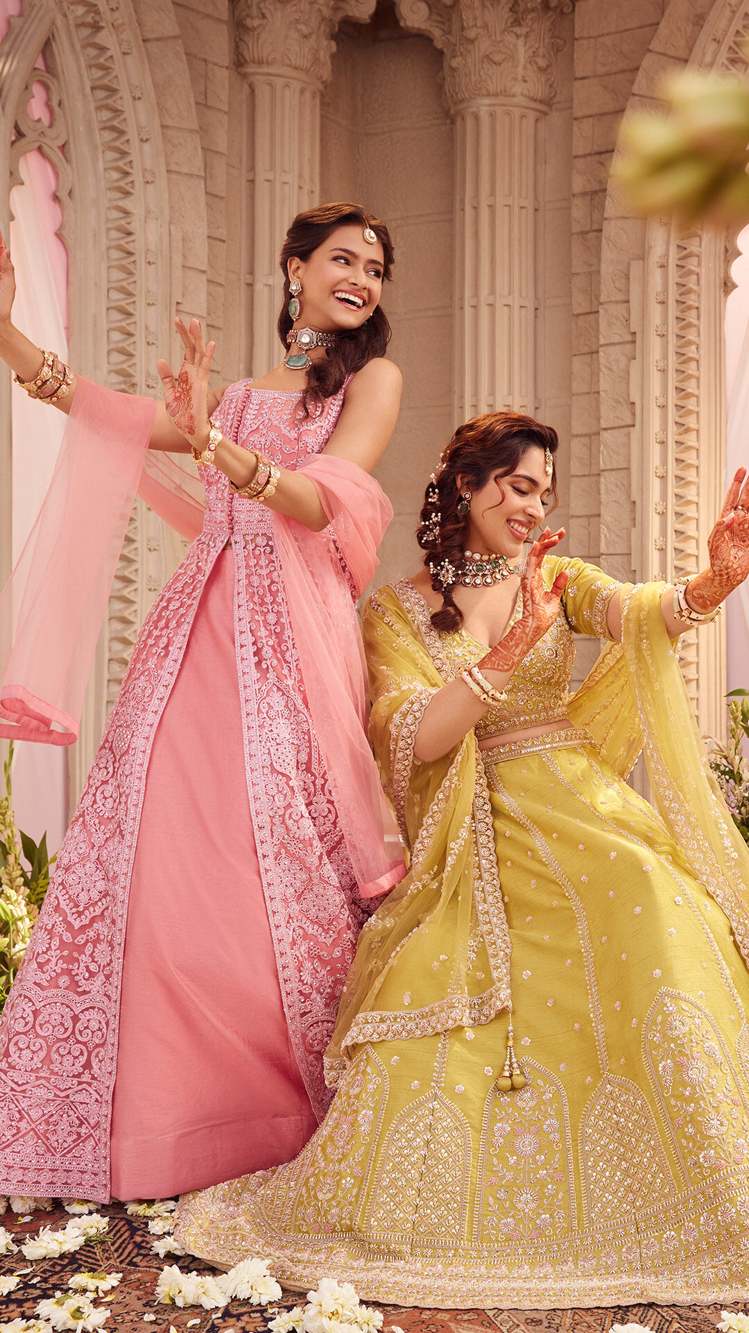 Bride and bridesmaid wearing pink and yellow leheng for wedding ceremony
